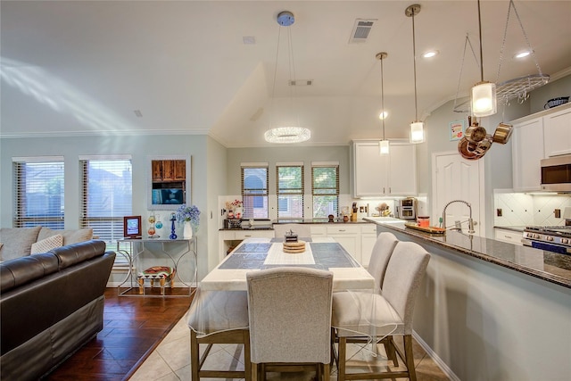 dining room featuring ornamental molding, dark tile patterned floors, visible vents, and a healthy amount of sunlight