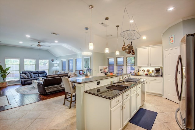 kitchen with pendant lighting, stainless steel appliances, visible vents, a kitchen island with sink, and white cabinetry