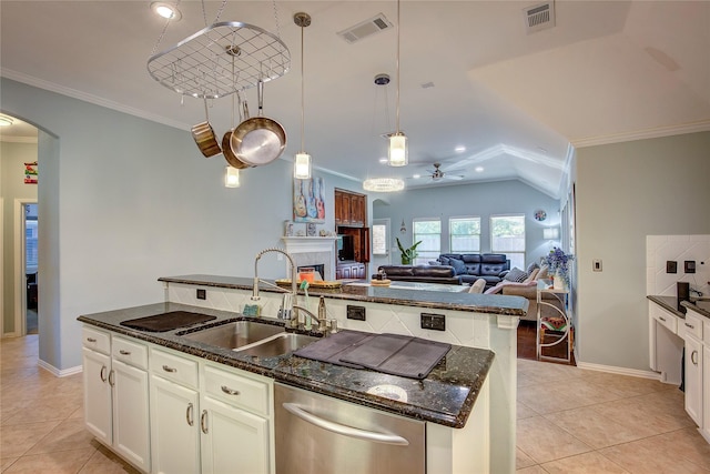 kitchen with arched walkways, a kitchen island with sink, a sink, and visible vents