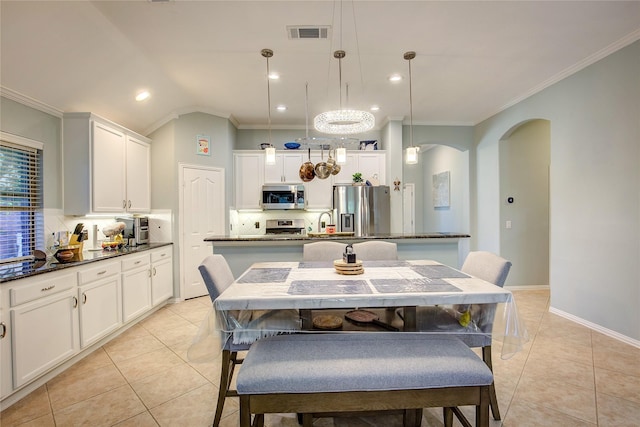 dining area featuring arched walkways, visible vents, and crown molding