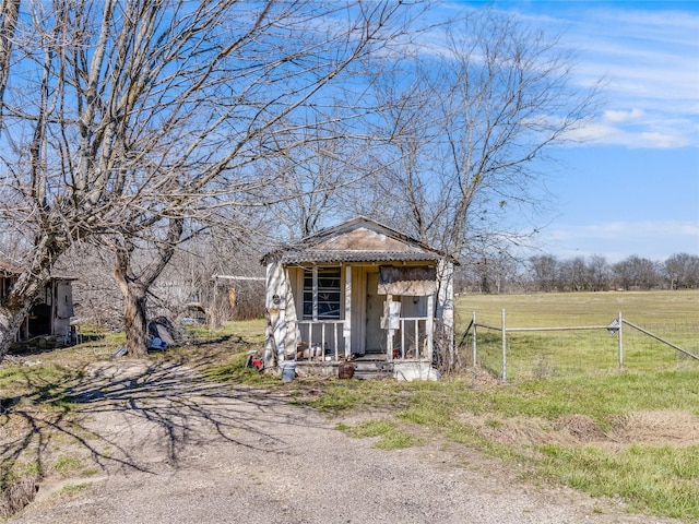 view of outbuilding with dirt driveway, an outdoor structure, and fence