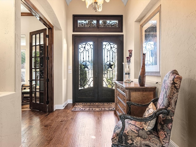 entryway with a textured wall, wood finished floors, baseboards, french doors, and an inviting chandelier