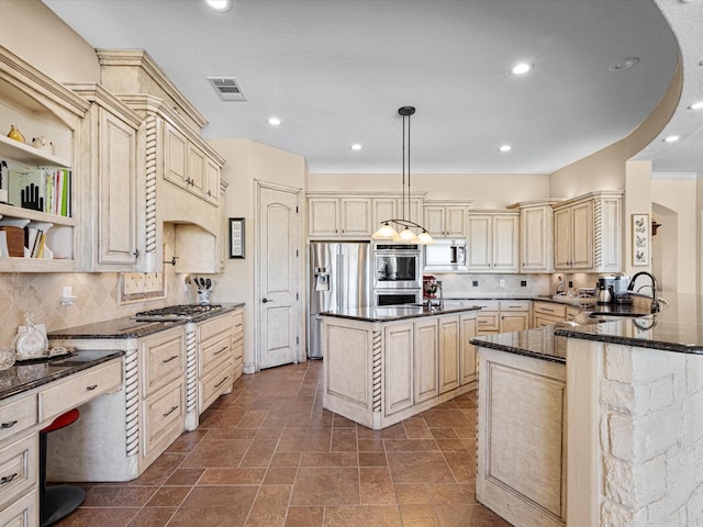 kitchen with stainless steel appliances, visible vents, cream cabinets, a sink, and dark stone counters