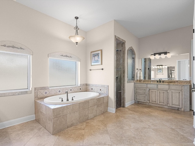 bathroom featuring a garden tub, vanity, tile patterned flooring, tiled shower, and baseboards