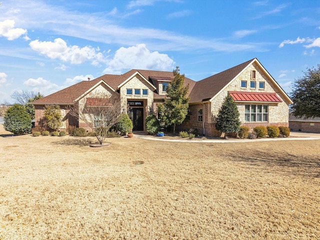 view of front of property featuring metal roof, stone siding, brick siding, and a standing seam roof