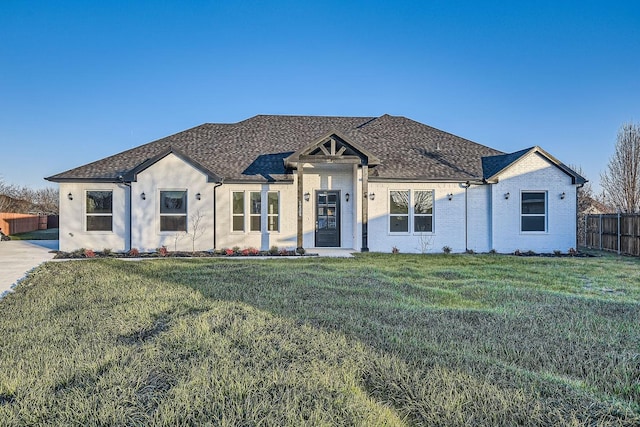 view of front of home featuring roof with shingles, a front yard, and fence