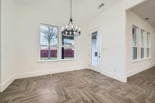 unfurnished dining area with an inviting chandelier, visible vents, and baseboards