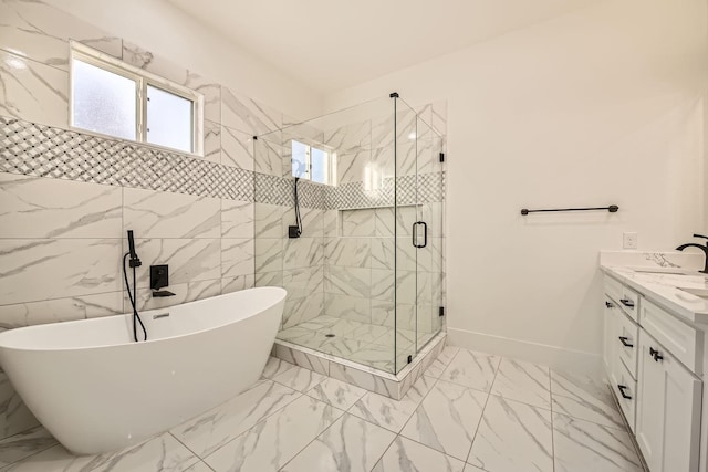 bathroom featuring marble finish floor, a shower stall, a freestanding bath, and vanity