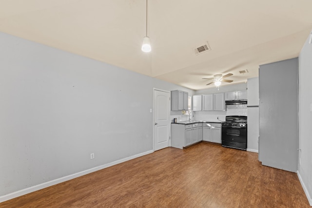 kitchen with under cabinet range hood, a sink, visible vents, black gas stove, and light countertops