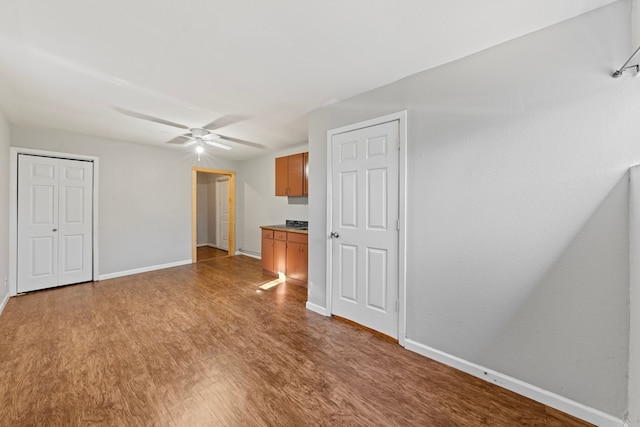 empty room with ceiling fan, baseboards, and wood finished floors