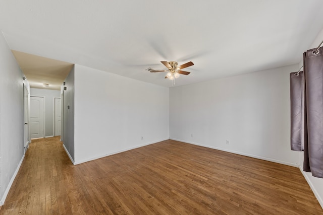 empty room with ceiling fan, baseboards, and wood finished floors