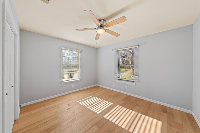 unfurnished bedroom featuring light wood-style flooring, baseboards, ceiling fan, and a closet