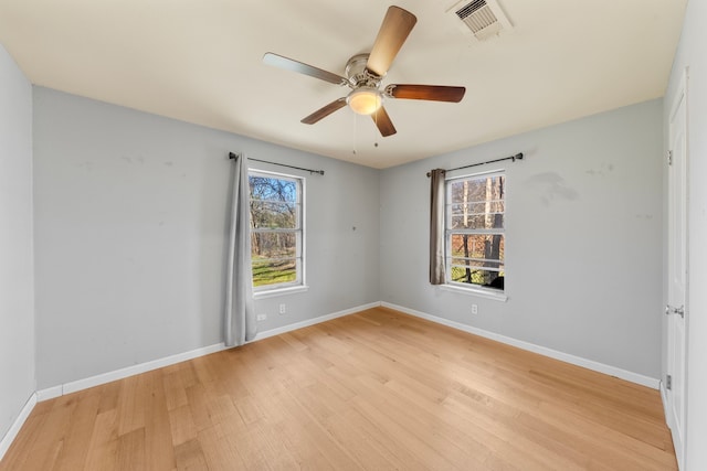 empty room with light wood-type flooring, visible vents, and baseboards