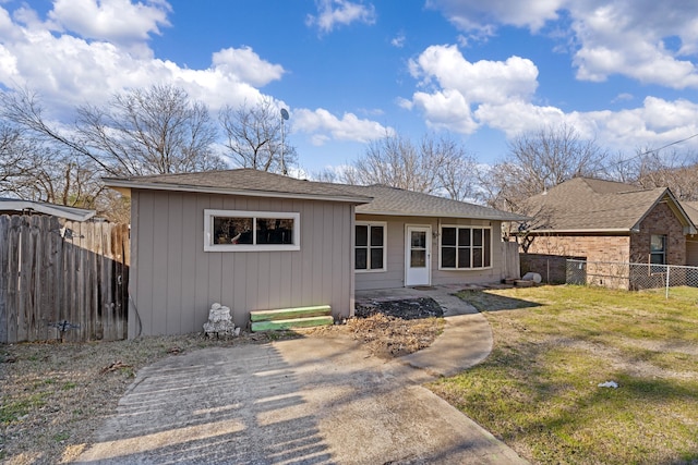 view of front of home with a shingled roof, a front yard, and fence