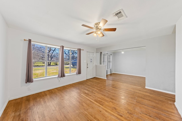 empty room featuring a ceiling fan, light wood-type flooring, visible vents, and baseboards