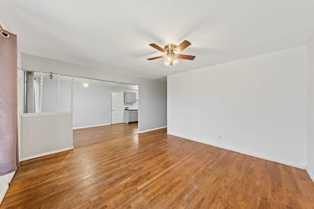 unfurnished living room with ceiling fan, baseboards, and wood finished floors