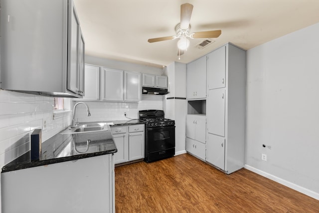 kitchen with black range with gas cooktop, under cabinet range hood, wood finished floors, a sink, and visible vents