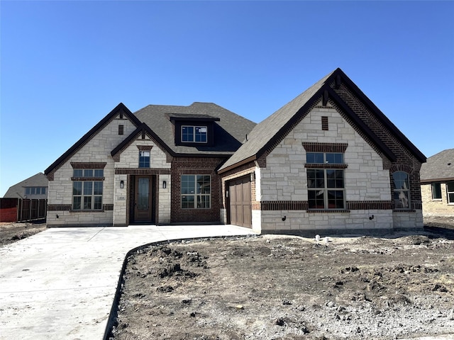 french provincial home with stone siding and an attached garage