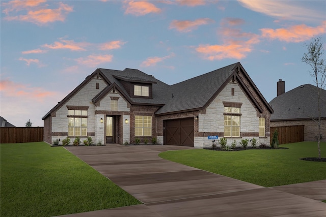 french country inspired facade featuring fence, driveway, and stone siding