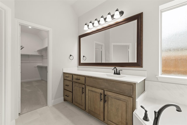 full bath with vanity, lofted ceiling, tile patterned floors, and a spacious closet