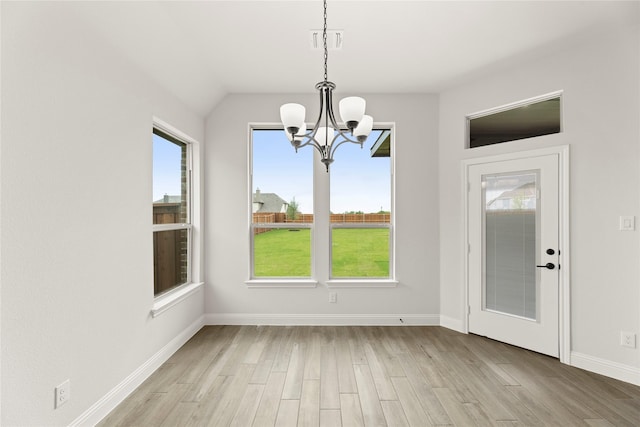 unfurnished dining area with visible vents, a notable chandelier, baseboards, lofted ceiling, and light wood-style floors