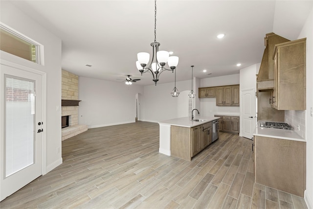 kitchen featuring open floor plan, light wood-style flooring, appliances with stainless steel finishes, and ceiling fan with notable chandelier
