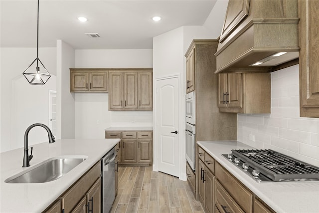 kitchen with decorative backsplash, custom range hood, a sink, light countertops, and stainless steel appliances