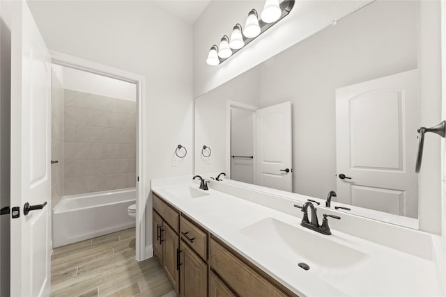 full bathroom with double vanity, toilet, a sink, and wood finished floors