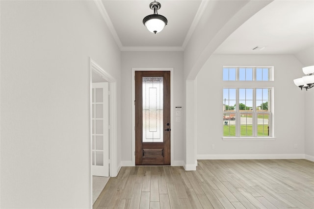 entryway featuring light wood-type flooring, arched walkways, a wealth of natural light, and visible vents