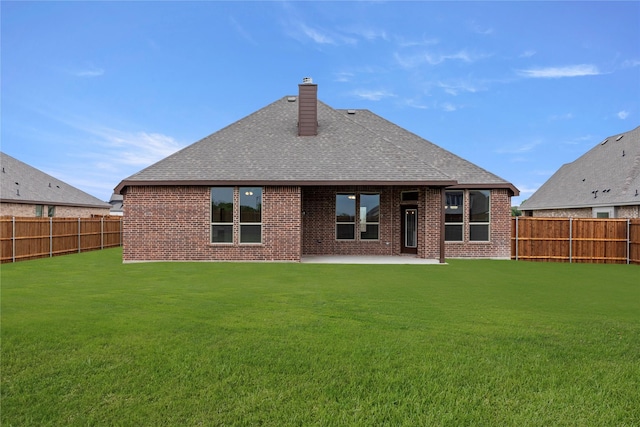 back of property with brick siding, a fenced backyard, and roof with shingles