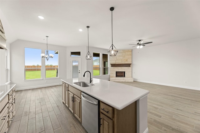 kitchen with a fireplace, light wood-style floors, a sink, ceiling fan with notable chandelier, and dishwasher