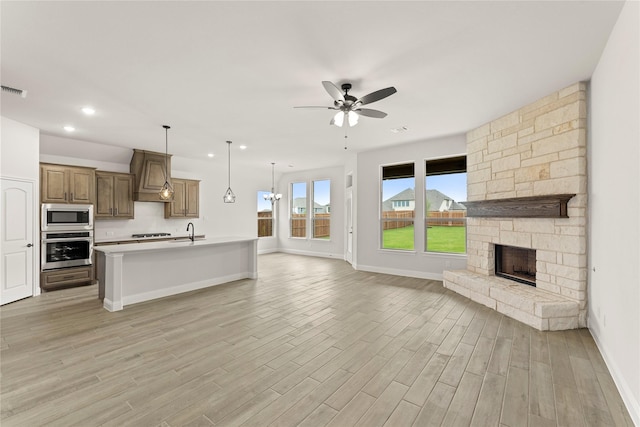 kitchen with custom exhaust hood, open floor plan, light countertops, a ceiling fan, and stainless steel appliances