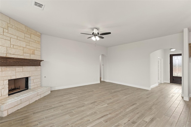 unfurnished living room with a ceiling fan, visible vents, arched walkways, baseboards, and light wood-style flooring