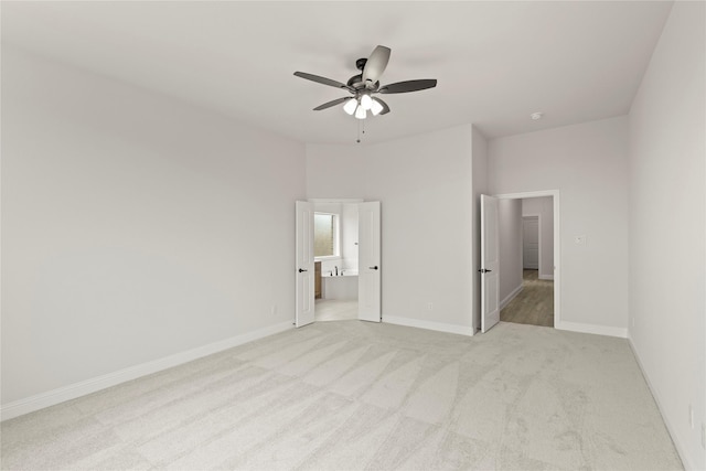 unfurnished bedroom featuring baseboards, a ceiling fan, connected bathroom, and light colored carpet
