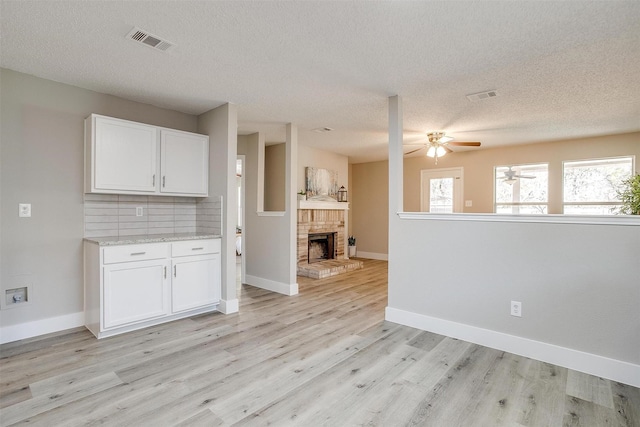 interior space featuring open floor plan, white cabinetry, visible vents, and backsplash