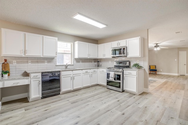 kitchen featuring white cabinets, decorative backsplash, light stone countertops, stainless steel appliances, and light wood-style floors