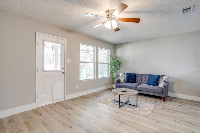 interior space featuring visible vents, baseboards, a ceiling fan, light wood-style flooring, and a textured ceiling