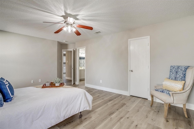 bedroom featuring baseboards, visible vents, light wood-style flooring, ceiling fan, and a textured ceiling