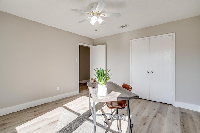 office space featuring light wood-type flooring, visible vents, and baseboards