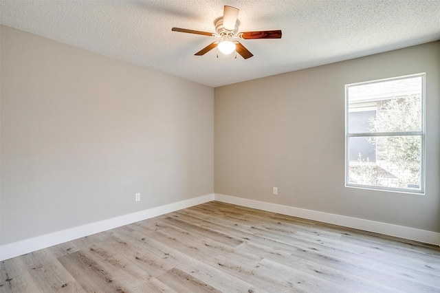 spare room featuring light wood-type flooring, a textured ceiling, baseboards, and a ceiling fan