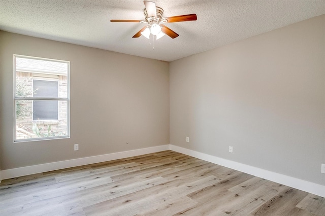 spare room featuring baseboards, plenty of natural light, light wood-style flooring, and a textured ceiling