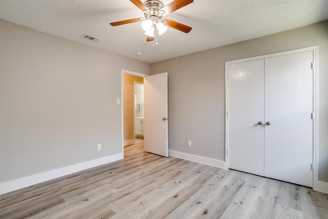 unfurnished bedroom featuring baseboards, visible vents, a textured ceiling, light wood-style floors, and a closet