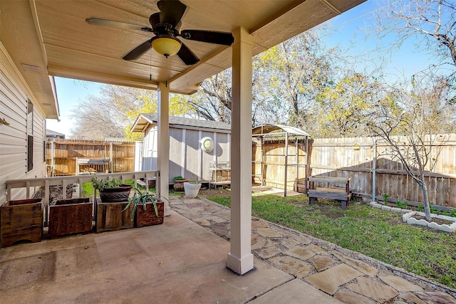 view of patio / terrace featuring an outbuilding, a fenced backyard, ceiling fan, and a storage unit