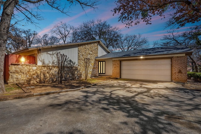 view of front of house with aphalt driveway, stone siding, and an attached garage