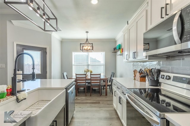 kitchen with stainless steel appliances, light countertops, and white cabinetry