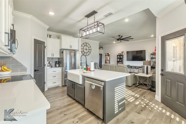 kitchen featuring stainless steel appliances, white cabinetry, light countertops, an island with sink, and pendant lighting