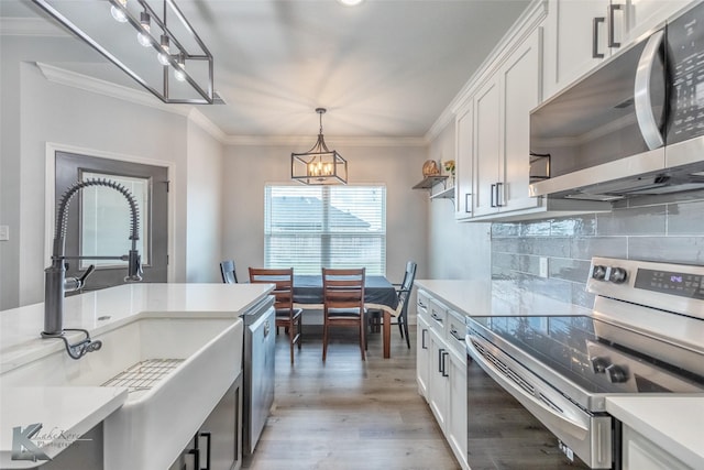 7001 Coldwater Dr, Abilene, TX 79601 - kitchen with appliances with stainless steel finishes, a chandelier, a sink, light wood finished floors, and white cabinetry