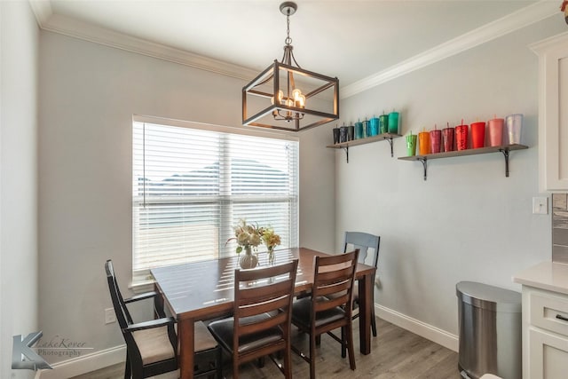 dining space featuring baseboards, a chandelier, crown molding, and wood finished floors