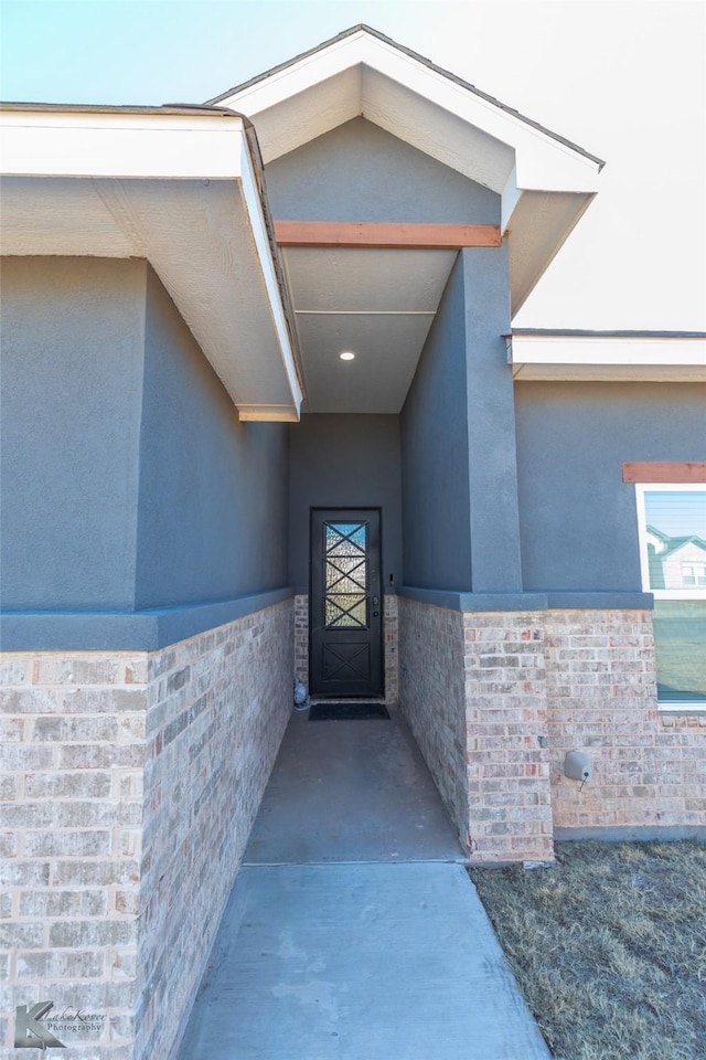 entrance to property featuring brick siding and stucco siding