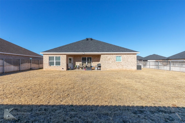 rear view of property featuring central AC unit, a fenced backyard, a yard, a patio area, and brick siding